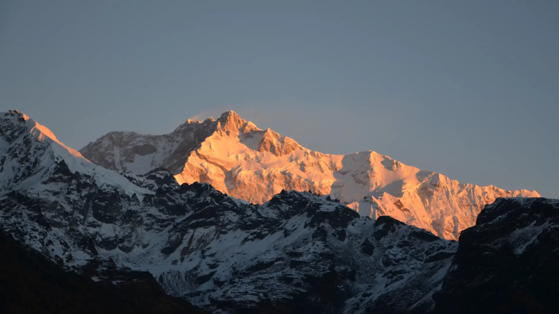 Kanchenjunga Kanchenjunga mountain peak glowing golden orange during sunrise in Sikkim Himalayas with snow-covered ridges and dramatic alpine landscape