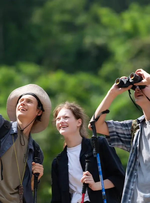 Sikkim nature & wildlife: Hikers with binoculars observing wildlife in a lush green environment.