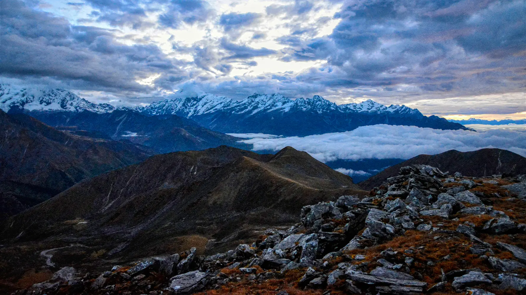 View from Danphebhir La on Uttarey–Singalila Circuit Trek with snow-capped Himalayas and cloud-covered valleys